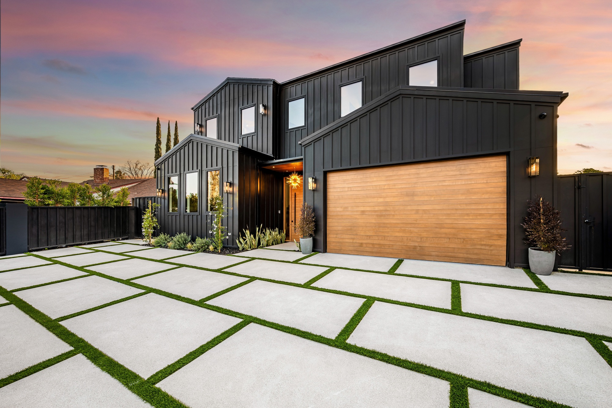 Modern black house with wooden garage door and geometric driveway.